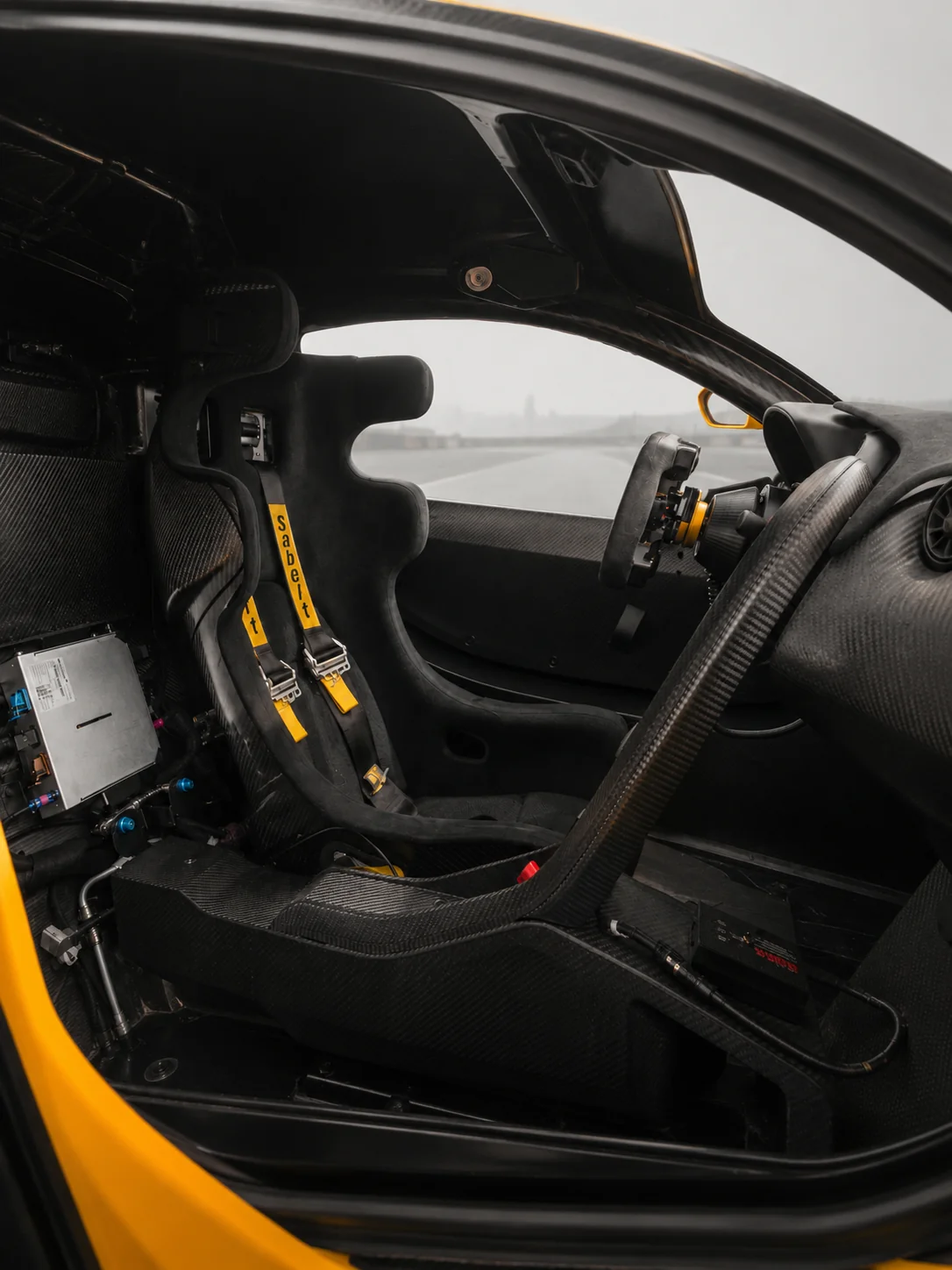 Cabin from the side through the open door: carbon tunnel, red switches and display